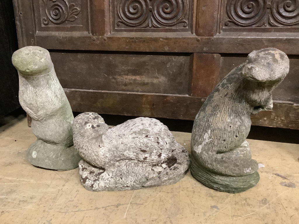 Three reconstituted stone otter garden ornaments, tallest 36cm
